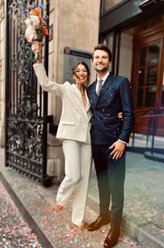 a man and woman standing next to each other in front of a building