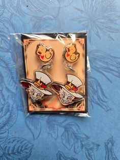 two cartoon character earrings in plastic packaging