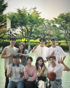 a group of people posing for a photo on a basketball court with trees in the background