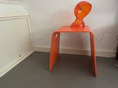 an orange chair sitting next to a white wall