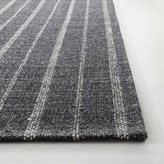 a gray and white rug with vertical stripes on the bottom, in front of a white floor