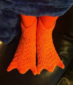 an orange knitted pair of socks with crochet on the legs and feet