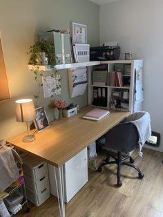 a desk with a lamp, bookshelf and other items on top of it