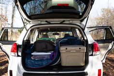 the back end of a white van with luggage in it's trunk and open hatchback