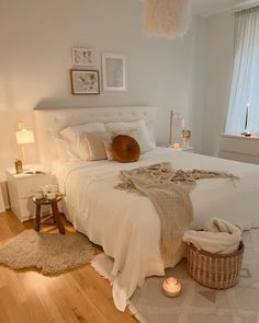 a bedroom with white walls and wooden flooring has a large bed, two nightstands, and pictures on the wall