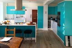 a kitchen with blue walls and wooden flooring, an island table in the middle