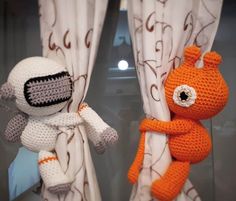 two crocheted stuffed animals hanging from curtains