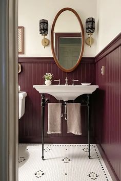 a white sink sitting under a mirror in a bathroom next to a wall mounted toilet