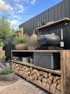 a wooden shelf with pots and pans on top of it next to a firewood pile