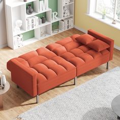 an orange couch sitting on top of a hard wood floor next to a book shelf