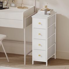 a small white desk with drawers and a lamp on the top shelf next to it