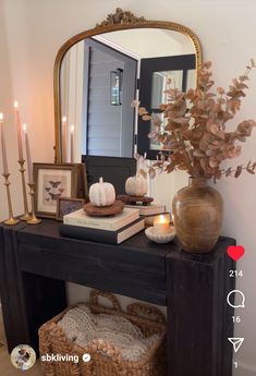 a black table topped with a vase filled with flowers next to a mirror and candles