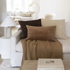 a living room filled with furniture and pillows on top of a white couch next to a window