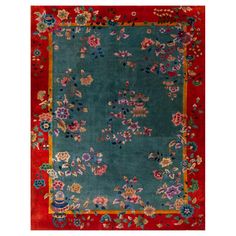 a blue rug with red border and flowers on the bottom, in front of a white background