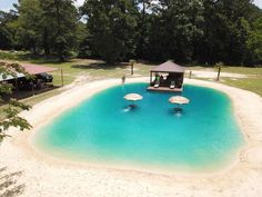 an empty swimming pool in the middle of a park with umbrellas and chairs around it