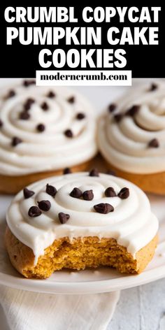 two pumpkin cupcakes with white frosting and chocolate chips are on a plate