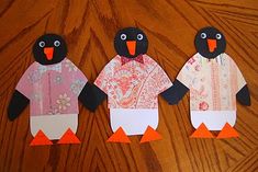 three penguins made out of paper sitting on top of a wooden table