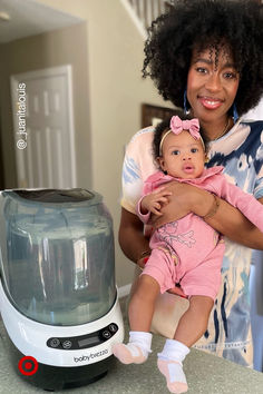 a woman holding a baby in her arms next to an air fryer and blender