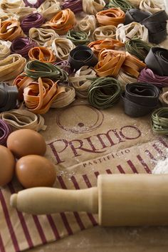 an assortment of pasta, eggs and rolling pin on top of a floured table