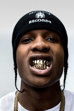 a man with his mouth open wearing a black hat and gold chain around his neck