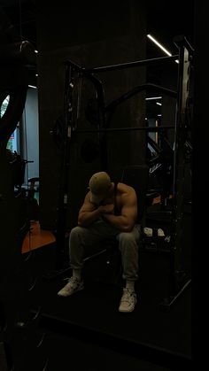 a man sitting on top of a bench next to a barbell machine in a gym