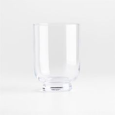 a clear glass is sitting on a white surface with no one around it and the bottom half empty