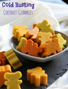 a bowl filled with orange, yellow and green bear shaped cookies on top of a table