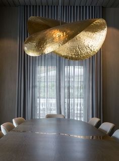 a dining room table with chairs and a large light fixture hanging from it's ceiling