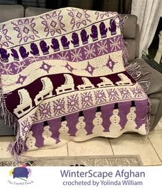 a purple and white afghan sitting on top of a couch