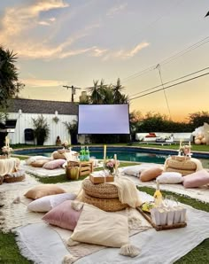 an outdoor movie is set up in the backyard with lots of pillows and blankets on the grass