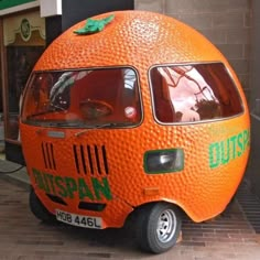 an orange car is parked in front of a building