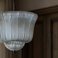 a light fixture hanging from the ceiling in a room with wood paneling and curtains