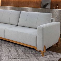 a white couch sitting on top of a wooden floor next to a gray and white rug