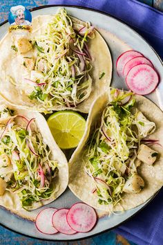 three tacos on a plate with radishes and lime