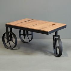 a wooden table with wheels on it and a gray wall in the backround