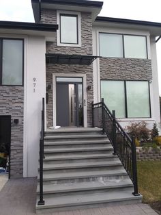 a house with stairs leading up to the front door and entry way, on a cloudy day