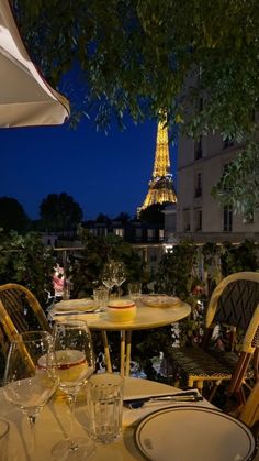 the table is set with wine glasses and plates in front of the eiffel tower