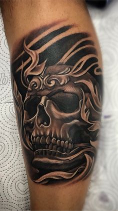 a man's arm with a skull and flames tattoo on the side of his leg