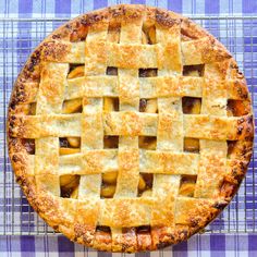 an apple pie on a blue and white checkered tablecloth with a latticed crust