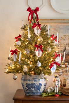 a decorated christmas tree in a blue and white china bowl with red bows on it