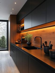 a kitchen with black cabinets and wooden counter tops, along with a large window that looks out onto the backyard