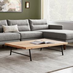 a living room with a gray couch and wooden coffee table in front of a window