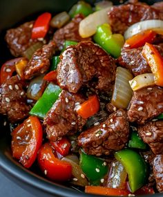 beef and peppers stir fry in a black bowl