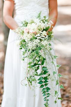 a woman holding a bouquet of flowers on her wedding day in front of the camera