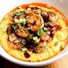 a bowl filled with shrimp and grits on top of a wooden table