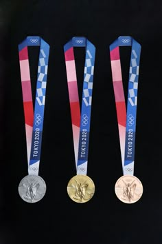 three olympic medals are displayed on a black surface with red, white and blue ribbons