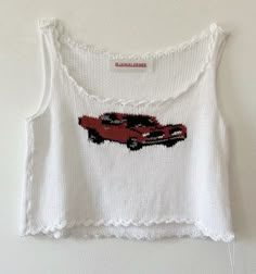 a white tank top with a red car embroidered on the front and back, hanging from a hook