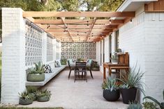 an outdoor covered patio with tables, chairs and potted plants on the side wall