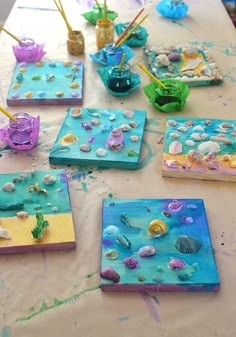 some little boxes that are sitting on a table covered in seaweed and seashells