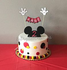 a mickey mouse birthday cake on a red tablecloth with name and number 2 candles